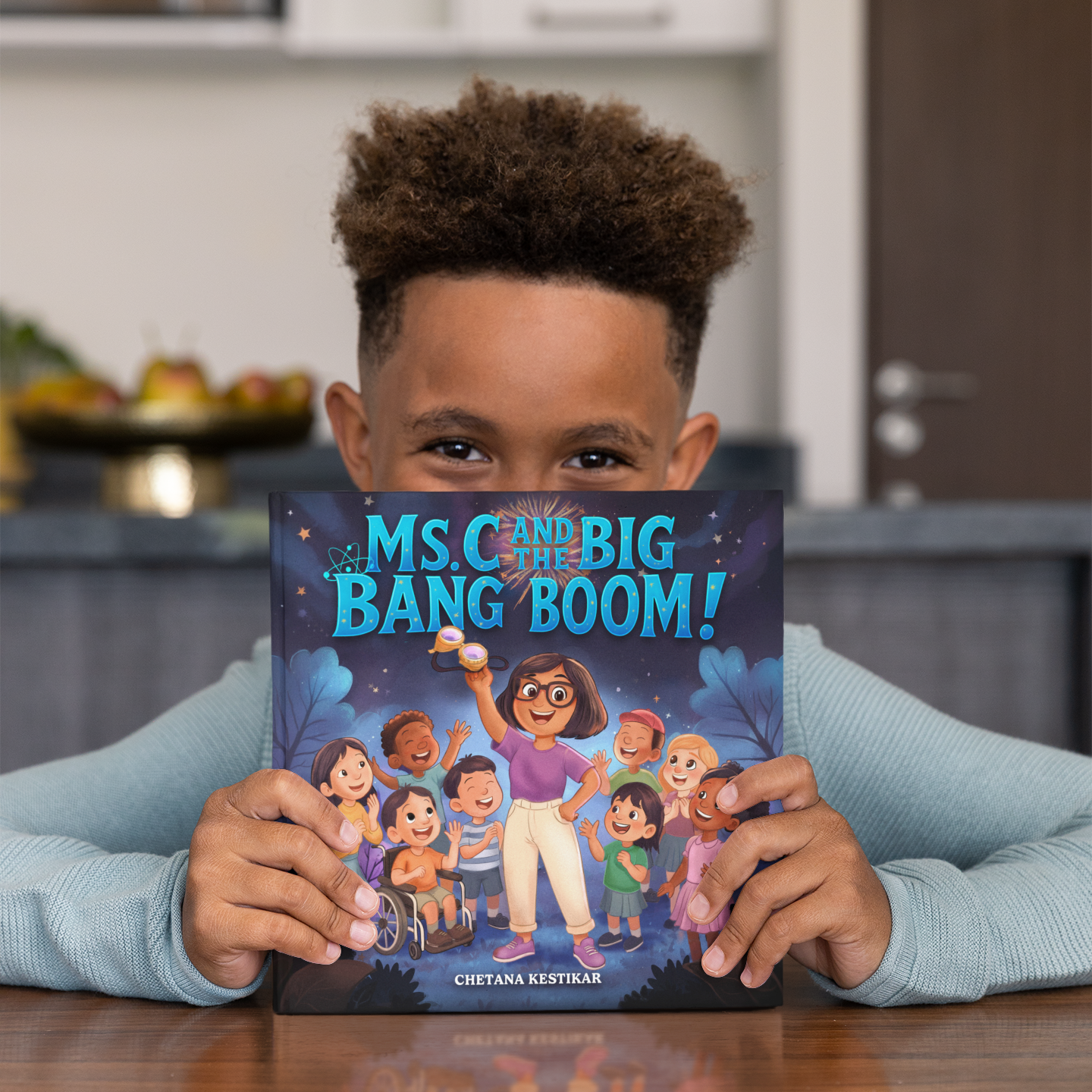 Child holding a book titled 'Ms C and the Big Bang Boom!'